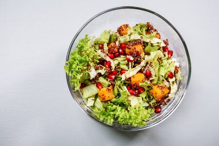Salad with kale, pumpkin, red quinoa and pomegranate in a glass bowl.の写真素材