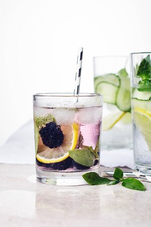 Summer refreshing drink, tonic with lemon, blackberry, cucumber and basil leaves on whiteの写真素材