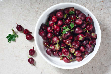 Ripe red gooseberries in a bowl on the kitchen table, top view.の写真素材