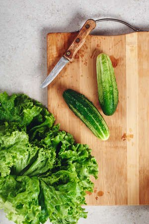 Fresh cucumbers and lettuce on a cutting board, top view.の写真素材
