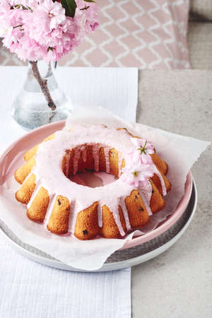 Festive Bundt cake with pink glaze, decorated with cherry flowers.
