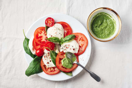 Caprese salad. Tomatoes, mozzarella cheese, basil leaves and pesto sauce.の写真素材
