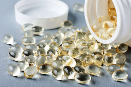 Yellow capsules of vitamin D on a gray surface.の写真素材