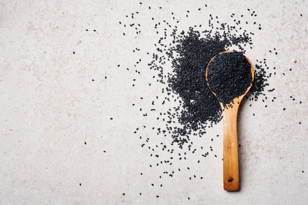 Black sesame seeds in a wooden spoon, top view.の写真素材