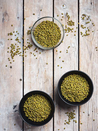 Raw mung beans in bowls on a wooden background, top view.の写真素材