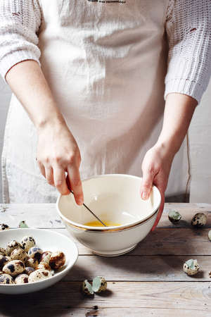 Woman whipping quail eggs in bowl, making mayonnaise.