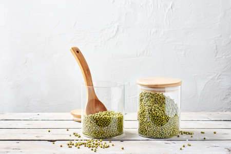 Two glass jars with raw mung beans on a wooden table.の写真素材