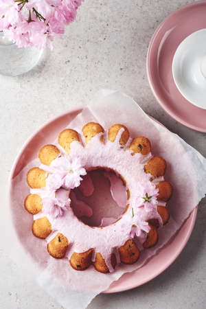 Festive Bundt cake with pink glaze and cherry flowers.の写真素材