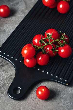 Vine of fresh cherry tomatoes on a dark background.の写真素材