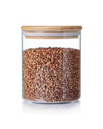 Dry buckwheat in a glass jar isolated on a white background.の写真素材