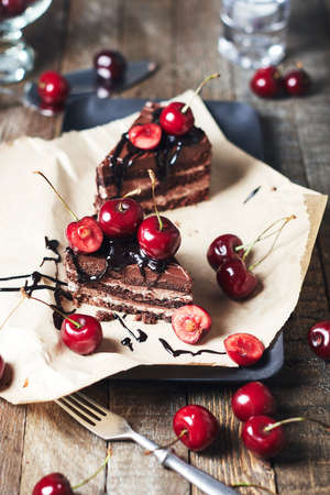 Two pieces of cake with fresh cherries on a wooden table.の写真素材