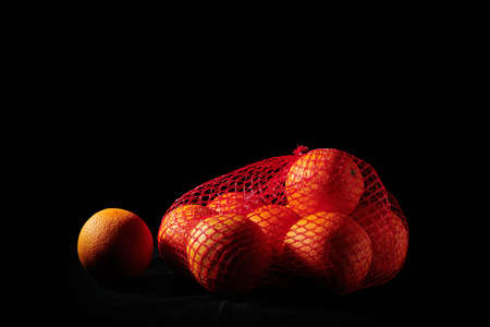 Ripe oranges in a mesh bag on a black background.の写真素材