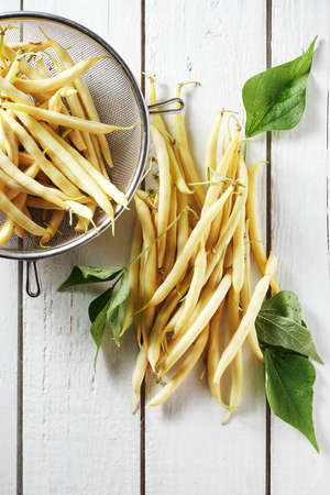 Yellow wax beans on a white wooden table.の写真素材