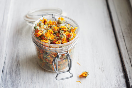 Dried marigold flowers in a jar on white wood, selective focus.の写真素材