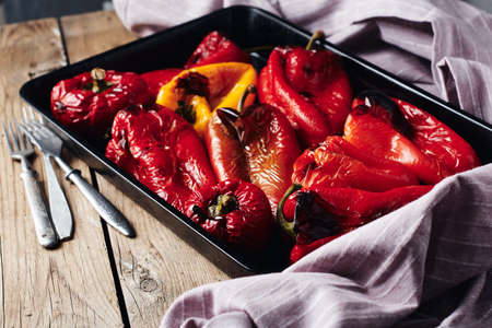 Roasted red and yellow peppers in baking tray on a wooden background.の写真素材