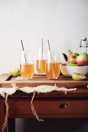 Organic apple cider in glasses with a straw on a wooden table.の写真素材