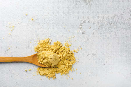 Mustard powder in a wooden spoon on a white background.の写真素材