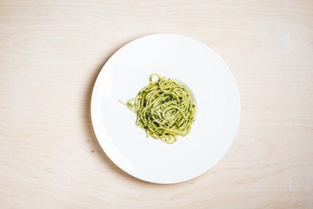 Spaghetti with pesto sauce in a white plate, top view.の写真素材