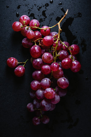 Branch of red grapes on a dark background, top view.
