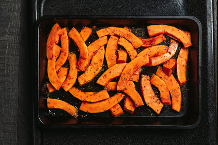 Pumpkin slices with spices on a baking sheet.の写真素材