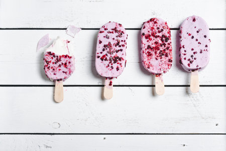 Violet berry ice creams on a white wooden background.