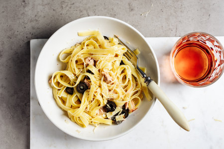 Tagliatelle pasta with tuna, olives and cheese on a marble background.の写真素材