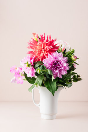 Bouquet of red and pink dahlias on a cream-colored background.の写真素材
