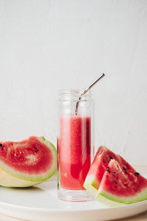 Bottle of chilled watermelon juice, watermelon slices on a white tray.の写真素材