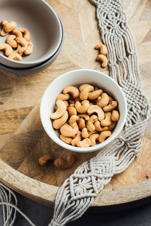 Roasted cashew nuts in a bowl on a wooden tray.の写真素材