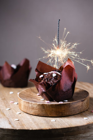 Festive chocolate muffin with sparkler on a dark background.の写真素材