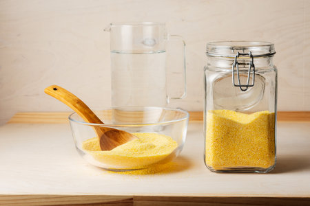Corn grits in a glass jar on a wooden table.の写真素材