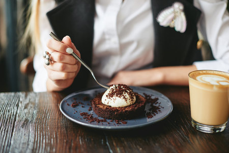 Girl eating chocolate dessert brown with white creamの写真素材