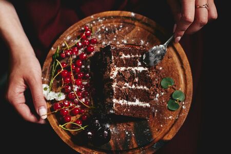 woman eating chocolate cake with berries red currantの写真素材