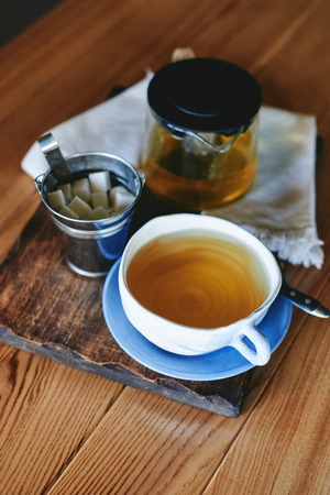Pottery mug and teapot with green tea on wooden tableの写真素材