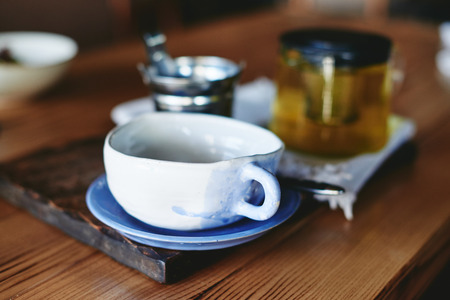 Pottery mug and teapot with green tea on wooden tableの写真素材