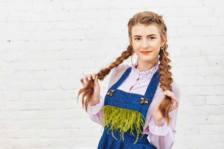Fashion photo of young girl posing over white brick wall backgroundの写真素材