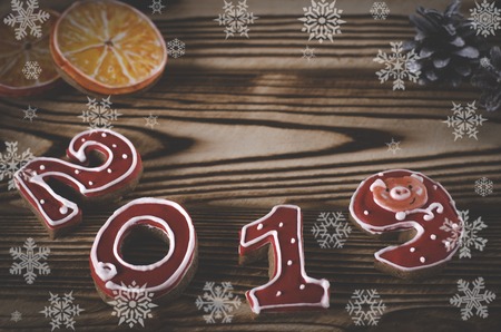 Christmas card on wood background gingerbread red numbers 2019 with slices of apelstina, buds covered with snow and white snowflakeの写真素材