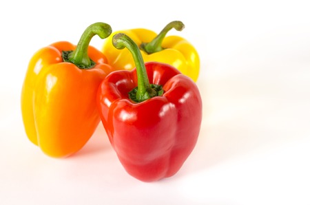 Juicy red, orange and yellow peppers with a green tail lies on a white background. isolatedの写真素材