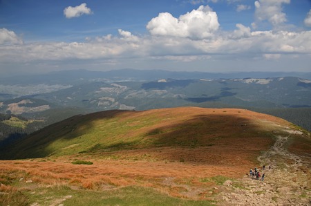 Beautiful view from the stone peaks of the mountain ranges of Hoverla Ukrainian Carpathian mountains covered with ancient conifer forests and autumn yellow grassの写真素材