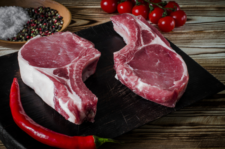 Raw marbled meat steak, pepper, herbs, garlic, old wooden background. Space for text. Beef Rib eye steak ready for cooking.の写真素材