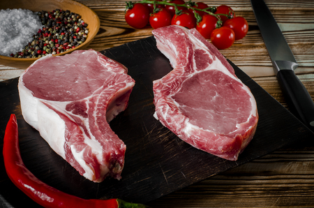 Raw marbled meat steak, pepper, herbs, garlic, old wooden background. Space for text. Beef Rib eye steak ready for cooking.の写真素材