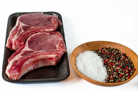 Raw marbled meat steak, pepper, herbs, garlic, old wooden background. Space for text. Beef Rib eye steak ready for cooking.の写真素材