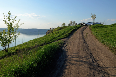 The huge river Dniester flows between high steep hills covered with spring lush green grass against the blue skyの写真素材