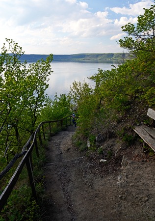 The huge river Dniester flows between high steep hills covered with spring lush green grass against the blue skyの写真素材