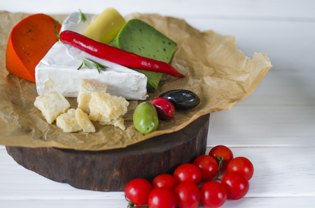 Mix cheese on dark background on wood board with grapes, honey, nuts, tomatoes and basil. Top view.の写真素材