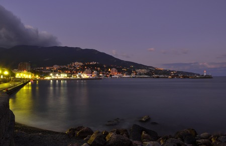 Evening Embankment of Yalta on the Black Sea coast on the background of mountains and sunset sky with cloudsの写真素材