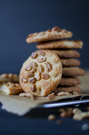 Homemade ruddy cookies with nuts lie pyramid on baking paper on a dark backgroundの写真素材