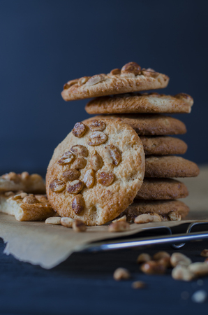 Homemade ruddy cookies with nuts lie pyramid on baking paper on a dark backgroundの写真素材