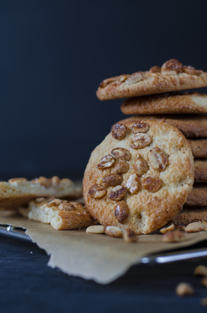 Homemade ruddy cookies with nuts lie pyramid on baking paper on a dark backgroundの写真素材