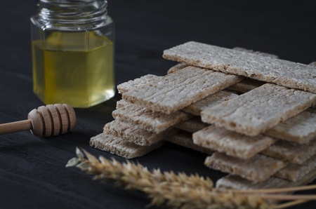 Healthy food. Air dietetic loaves lie on a dark wooden table on a dark background next to the ears of wheat and honeyの写真素材
